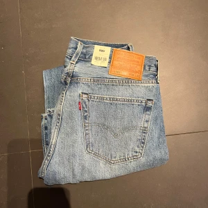 Helt nya Levis 501 jeans - Säljer ett par klassiska Levis 501 jeans i ljusblå denim. De har en straight passform och är slitna med hål för en trendig look. Perfekta för en avslappnad stil. Nypriss 1349 mitt endast 500. 