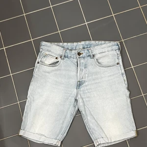 Ljusblå jeansshorts från H&M - Snygga ljusblå jeansshorts från H&M med klassisk femficksdesign och knappgylf. Tillverkade i 100% bomull för en bekväm passform. Low waist shorts 30 CN 170/76A