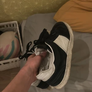 Svartvita sneakers - Säljer ett par svartvita sneakers med snörning. Skorna har en klassisk design med svart och vit färgkombination och en vit sula. Perfekta för en avslappnad stil.