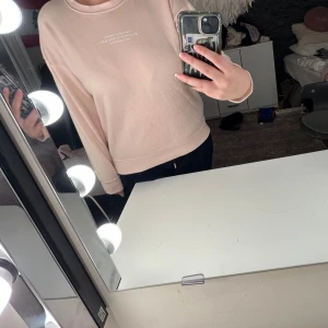 Beige/rosa sweatshirt från Champion - Säljer en stilren sweatshirt. Tröjan har en avslappnad passform med långa ärmar och rund halsringning. Perfekt för en casual look. Hör av dig vid intresse!
