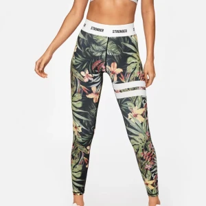 Blommiga leggings från Stronger - Snygga leggings med tropiskt blommönster i grönt, rosa och gult. De har vita ränder runt låren och en elastisk midja med Stronger-logga. Perfekta för träning eller en färgglad vardagslook. Inga skärskilda defekter💐🌼💞🌸🌴