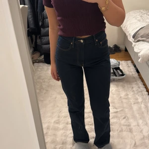 Mörkblå jeansbyxor - Snygga mörkblå jeansbyxor med hög midja och bootcut-stil. Perfekta för en avslappnad look. Byxorna har klassiska fem fickor och en knappgylf.