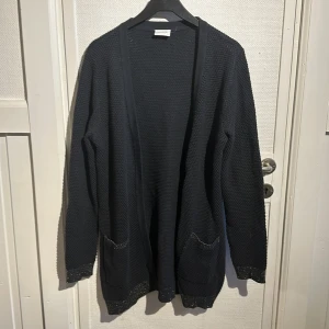 Svart stickad kofta från VILA - Säljer en svart stickad kofta från VILA i storlek M. Koftan har långa ärmar och praktiska fickor framtill. Perfekt för kyliga dagar och enkel att matcha med olika outfits. Hör av dig vid intresse!