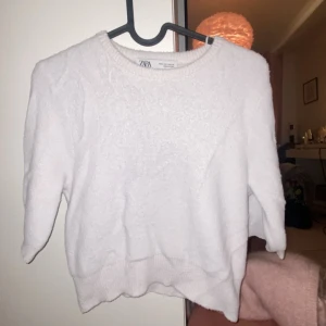 Vit tröja från Zara - Säljer en stilren vit tröja från Zara. Tröjan har en rund halsringning och trekvartsärmar, perfekt för en avslappnad look. Den är mjuk och bekväm, idealisk för både vår och höst. Tröjan är använd fåtal gånger och har inga märken eller fläckar. Säljer pågrund av att den är för liten 