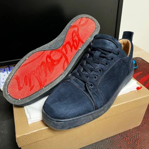 Christian Louboutin skor - Snygga mörkblå sneakers från Christian Louboutin i mocka med den ikoniska röda sulan. Skorna har snörning och en stilren design som passar perfekt för en trendig look. Tillverkade i Italien och kommer med originalförpackning och vårdinstruktioner. Storlek 43, skick 8/10 mockan är i jätte bra skick men sulan är lite sliten bara. Pris kan diskuteras 