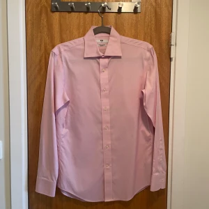 Rosa slim fit non-iron skjorta - En rosa skjorta från Uniqlo i fint skick, som har använts 1-2 gånger innan. Passar fint till diverse festligheter. Den har slimmad passform, består av 100% bomull och behöver inte strykas efter tvätt. Frågor? Skicka ett dm.