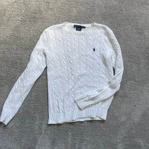 Ralph Lauren kabelstickad tröja - Säljer denna tröja från ralph lauren. Vit med mörkblått märke. Den är i jättebra skick. Storlek M i dam. Skriv vid funderingar.