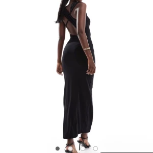 Svart klänning  - Helt oanvänd med prislappen kvar, jättefin svart maxiklänning som sitter såå fint på kroppen. Öppen rygg och lite drapering över klänningen. 