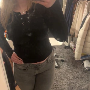 Svart långärmad topp med snörning - Snygg svart långärmad topp med snörning framtill. Passar bra till både jeans, soft pants och kjol. Storlek XS-M