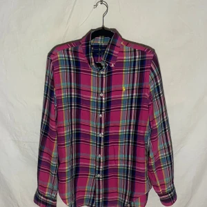 Rutig skjorta från Ralph Lauren - Snygg rutig skjorta från Ralph Lauren i en mix av rosa, blå, grön och gul. Skjortan har långa ärmar och knappar framtill. Perfekt för en avslappnad stil med sin relaxed fit.