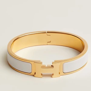 Guld och vitt armband - Äkta!! hemres armband Elegant armband i guld med vit emaljdetalj. Perfekt för att ge en stilren touch till din outfit. Armbandet har en unik design med ett H-format spänne.