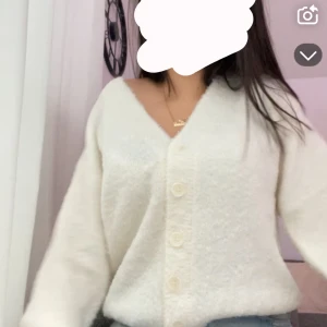 Vit fluffig kofta med knappar - Mysig vit kofta med knappar framtill. Den har en v-ringad design och är perfekt för kyliga dagar. Koftan är fluffig och ger en avslappnad look. Den är oversized, jag har storlek Xxs som även kan passa Xxs-M. Mycket bra skick då jag bara har använt den 1 gång 