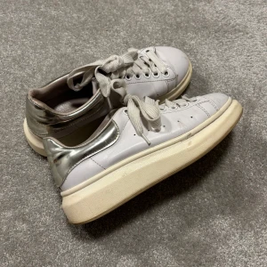 Alexander Mcqueen skor - Säljer dessa snygga vita/silvriga Alexander mcqueen skor för tjejer! Skorna i ganska bra skick, syns att de använts och har lite smådefekter men fortfarande mycket liv kvar i dem! Size 38. Skriv vid funderingar!