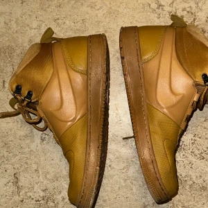 Bruna sneakers från Nike - Snygga bruna sneakers från Nike med snörning och robust sula. Perfekta för höst och vinter med sin slitstarka design och bekväma passform.