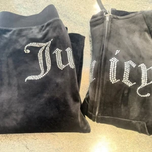 Svart velour hoodie från Juicy Couture - Säljer en svart velour hoodie från Juicy Couture med glittrande stenar som bildar texten 'Juicy' på framsidan. Den har en dragkedja och långa ärmar, perfekt för en avslappnad stil.