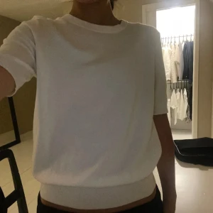 Vit kortärmad tröja - Snygg och enkel vit tröja med korta ärmar. Perfekt för en stilren look. Tröjan har en rund hals och är gjord i ett mjukt material.