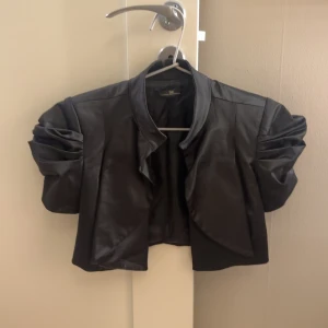 Svart bolero  - Svart bolero i sidenmaterial. Går att knäppa där fram om man så vill🥰står ingen storlek men skulle säga att den är s. Super snygg!!!