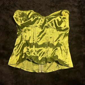 Grön korsett från PLT - Snygg grön korsett i glansigt material från PrettyLittleThing. Den har en dragkedja bak och en smickrande passform. Perfekt för att ge en extra touch till din outfit.