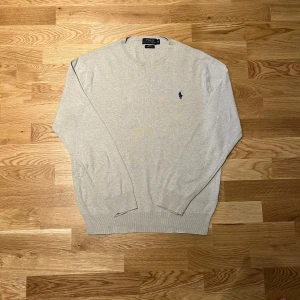 Beige tröja från Ralph Lauren - Säljer en beige tröja från Ralph Lauren i slim fit. Tröjan är tillverkad av mjuk pima bomull och har en klassisk rund halsringning. Den har långa ärmar och en diskret logga broderad på bröstet. Perfekt för en avslappnad men elegant look.