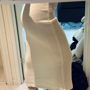 Vit stickad klänning - Säljer en stilren vit stickad klänning med tight passform. Klänningen är lång och perfekt för kyligare dagar. Den har en enkel design utan ärmar och är gjord i ett mjukt material som ger en bekväm känsla. Passar perfekt för s/m/l storlek