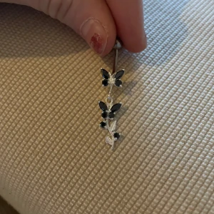 Silverfärgat Navelpersing med fjärilar - Snyggt silverfärgat Navelpersing med hängande fjärilar dekorerade med marinblåa  stenar. Perfekt för att ge en elegant touch till din stil. 