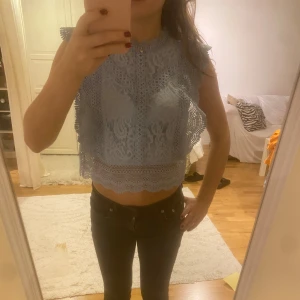 Ljusblå spetsblus - Säljer en söt ljusblå blus i spets med volangdetaljer. Blusen är ärmlös och har en croppad passform med spetsdetaljer 