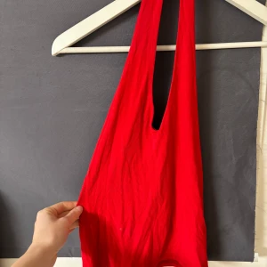 Röd väska från Twilfit - Snygg röd väska från Twilat i storlek S. Tillverkad i Italien med en blandning av viskos och elastan för en mjuk och stretchig känsla. Perfekt för att bära med sig det nödvändigaste med stil.