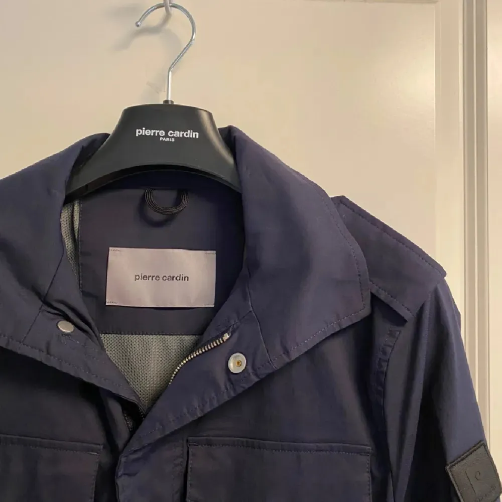 Snygg mörkblå jacka från Pierre Cardin med långa ärmar och flera praktiska fickor. Jackan har en stilren design med knappar och dragkedja framtill. Perfekt för en stilren look. Med en väst under funkar den perfekt till vinter! ✅❄️. Takit.