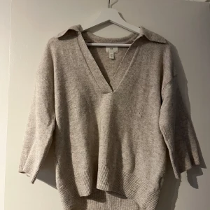 Beige tröja med v-ringning - Säljer en stilren beige tröja med v-ringning och trekvartsärmar. Perfekt för en avslappnad look. Tröjan har en mjuk och bekväm känsla.