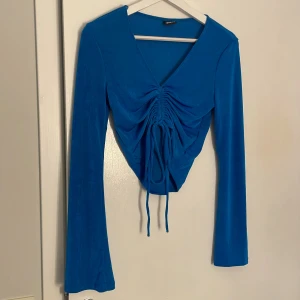 Blå långärmad topp med snörning - Snygg blå långärmad topp med v-ringning och snörning framtill. Väldigt Stretchig. Från gina