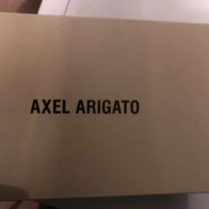 Skokartong från Axel Arigato - En skokartong från Axel Arigato med tillhörande skyddspåse. Perfekt för att förvara eller transportera dina sneakers.