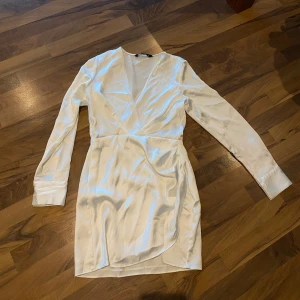 Vit omlottklänning från Zara - Elegant vit omlottklänning från Zara med långa ärmar och v-ringad design. 