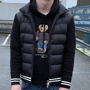 Moncler Cardigan - Snygg svart puffercardigan från Moncler med dragkedja och ribbade detaljer i vitt och svart. Jackan har långa ärmar och en quiltad design som ger extra värme, ganska tjock och otrolig isolering i ärmarna. Storlek 1(S) men passar M Perfekt för kyligare dagar! Har du frågor eller vill se mer utav jackan är det bara att höra av dig, svarar alltid fort. Endast seriösa ✅