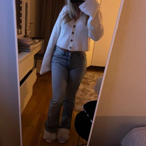 Vit ribbad kofta - Säljer en mysig vit ribbad kofta med knappar framtill. Koftan är croppad och har långa ärmar. 