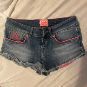 denim shorts med rosa detaljer - typ lågmidjade mini shorts med lite stretch 🩷obs jag som är storlek xs kan inte dra upp dragkedjan‼️skriv för mått