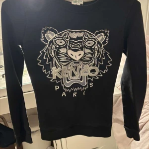 Kenzo tröja - Säljer en svart tröja från Kenzo, köpt på kenzos egna hemsida för ca 4-5 år sedan. Tröjan har långa ärmar och är tillverkad i ett mjukt material. Använd ett fåtal gånger, så den är i väldigt fint skick. Säljer för att den bara legat i garderoben och tagit upp plats. 