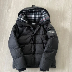 Burberry jacka - Tja, säljer en svart burberry puffer jacka. Storleken är 4 vilket motsvarar ungefär M/L. Jackan har inga defekter och den är varm, skön och håller dig varm även under de kallaste vinterdagarna. Säg till om du undrar något eller vill ha fler bilder.