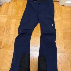 Mörkblå peak performance skidbyxor - Säljer mina peak performance skidbyxor i färgen marinblå med svarta detaljer. Jättesköna med mörkgrå fleece inuti. Säljer för att som ni ser så är dom alldeles för korta för mig. Normala i storleken. Använda endast 2 veckor skidsäsong