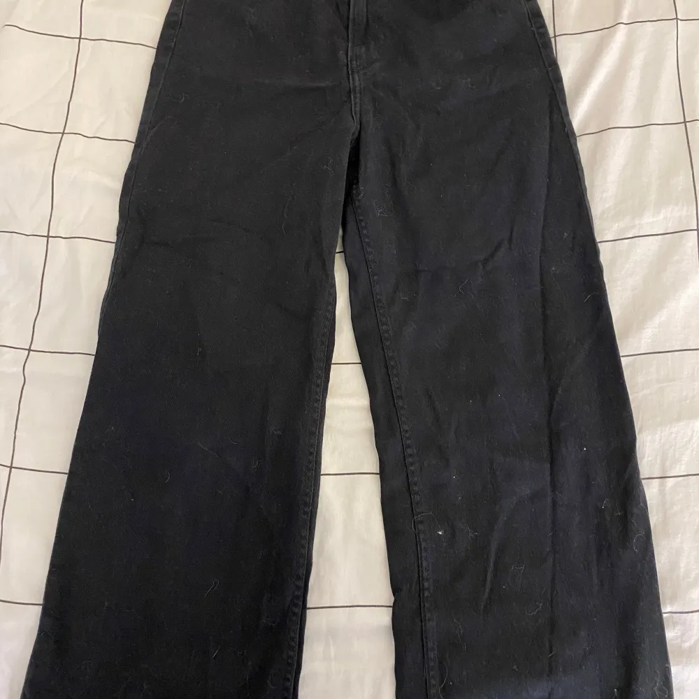 Snygga svarta jeansbyxor från H&M Divided med en klassisk femficksdesign. Byxorna har en knapp och dragkedja framtill och är tillverkade i ett slitstarkt material. Perfekta för en stilren look.. Farkut & Housut.