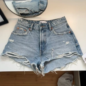 Blå jeansshorts - Säljer ett par snygga blå jeansshorts från Zara med slitna detaljer och råa kanter. Perfekta till sommaren🩷🩷 
