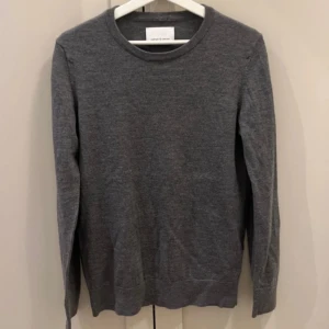 Grå merinoulltröja - Säljer en stilren grå tröja från Samsoe samsoe  i 100% merinoull. Tröjan är strl M men sitter mer som XS perfekt för kyligare dagar. Den är mjuk och bekväm, idealisk för både vardag och mer uppklädda tillfällen.