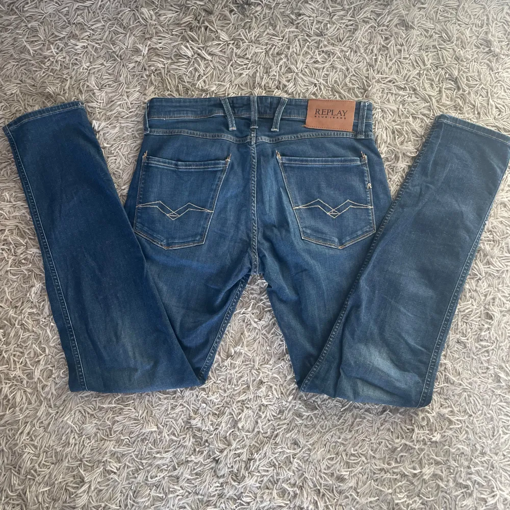 Snygga blå jeans från Replay med klassisk femficksdesign och snygga sömmar på bakfickorna. De har en knappgylf och är perfekta för en avslappnad stil. Märkeslappen i läder på baksidan ger en extra touch.. Farkut & Housut.