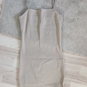 Beige ribbad klänning - Snygg beige ribbad klänning med smala axelband. Perfekt för en stilren look. Klänningen har en tight passform som framhäver figuren. 💕