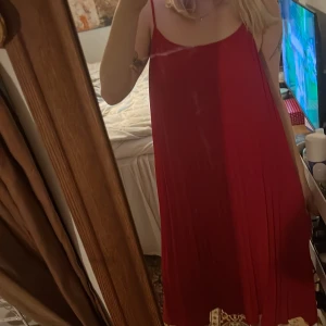 Röd plisserad klänning från h&m - Säljer en röd plisserad klänning med smala axelband. Klänningen har en luftig passform och är perfekt för varma dagar. Den är knälång och har en enkel men stilren design.