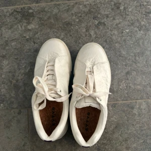 Vita sneakers från Eytys - Säljer ett par vita sneakers från Eytys i modellen Doja. Skorna är tillverkade i läder med en stilren design och snörning. Perfekta för en avslappnad stil. Använt fåtal gånger då dom är lite för stora