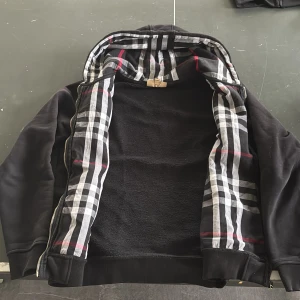 Svart Burberry hoodie - Säljer denna feta burberry hoodie. Vet ej om den är äkta, skick är 9/10 finns inga defekter förutom att man se lite användning annars ny. Några funderingar så är det bara skriva 