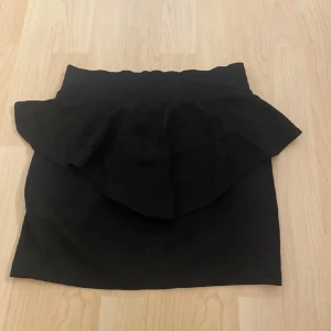 Svart kjol med volang - Snygg svart kortkjol med volangdetalj. 