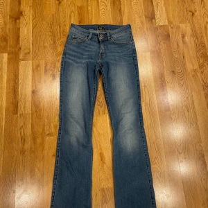 Utsvänga lågmidjade Lee jeans - Jeansen är lågmidjade och utsvängda/flare. Storlek W28 L33 och är stretschiga. Dom är oanvända och har inga skador mellan benen förutom en liten fläck där bak. Kom privat för fler bilder💗