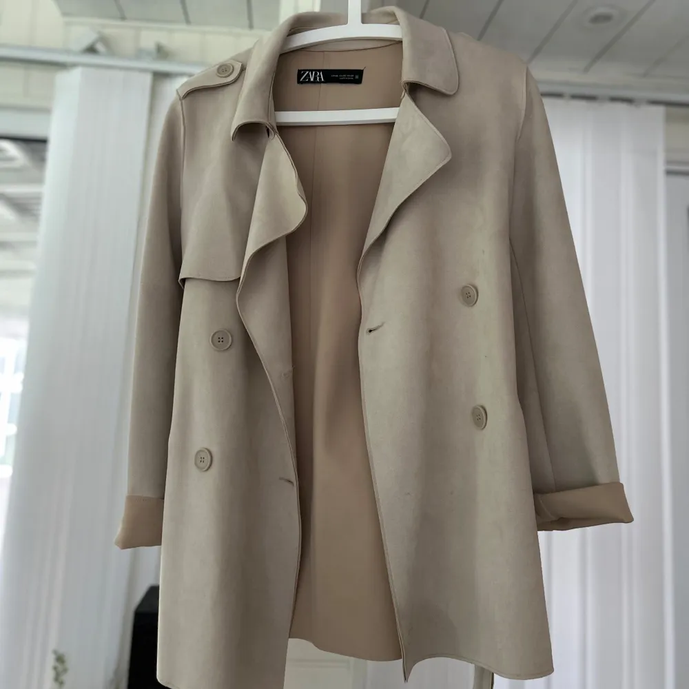 Säljer en superfin beige trenchcoat från Zara i storlek s/xs. Den har en klassisk design med knappar och ett bälte i midjan för en snygg passform. Perfekt för vår och höst! Ärmarna är långa och kappan har en stilren krage.🤎. Jackor.