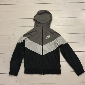 Nike jacka  - Nike träningsjacka i grått, svart och vitt i nyskick. Jackan har en luva, dragkedja och fickor. 
